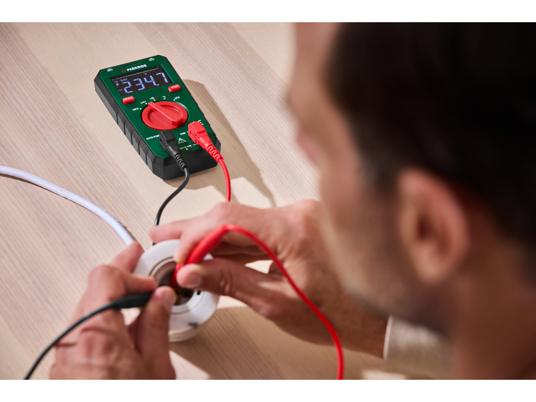 Een man gebruikt een Parkside multimeter voor elektrische metingen.