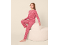 Meisje in roze pyjama met stippen zittend op een witte poef