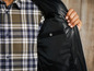 Een man draagt ​​een zwart jack met een geblokt overhemd eronder.