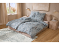 Slaapkamer met blauw bloemig beddengoed, bed en vloerkleed.