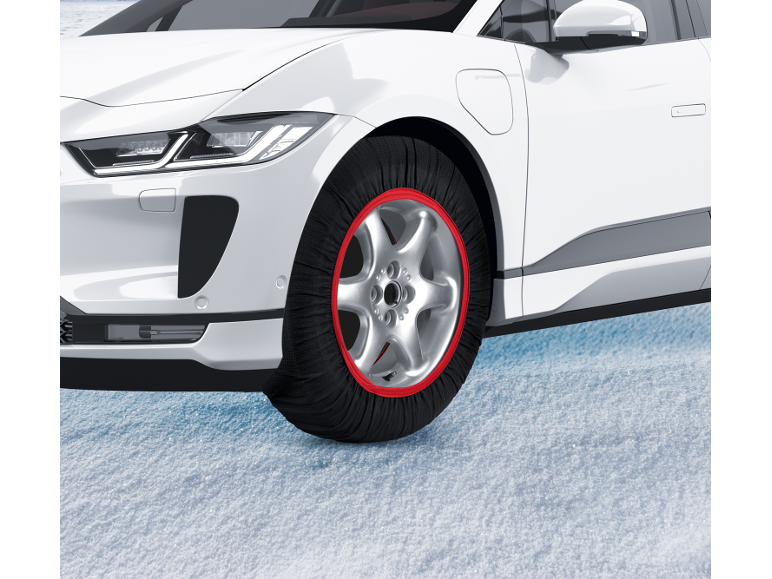Witte elektrische auto met rode textiele sneeuwkettingen op sneeuw.