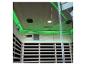 Interieur van een moderne sauna met groene LED-verlichting, houten lattenbanken en een bedieningspaneel.
