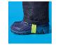 Zwarte broek en blauwe laarzen met een neongroene band op een blauwe achtergrond.