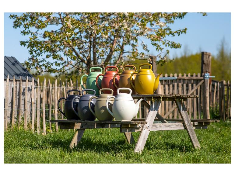 Kleurrijke gieters op een houten picknicktafel in de tuin.