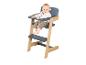 Lachende baby zit in een houten en grijze kinderstoel.