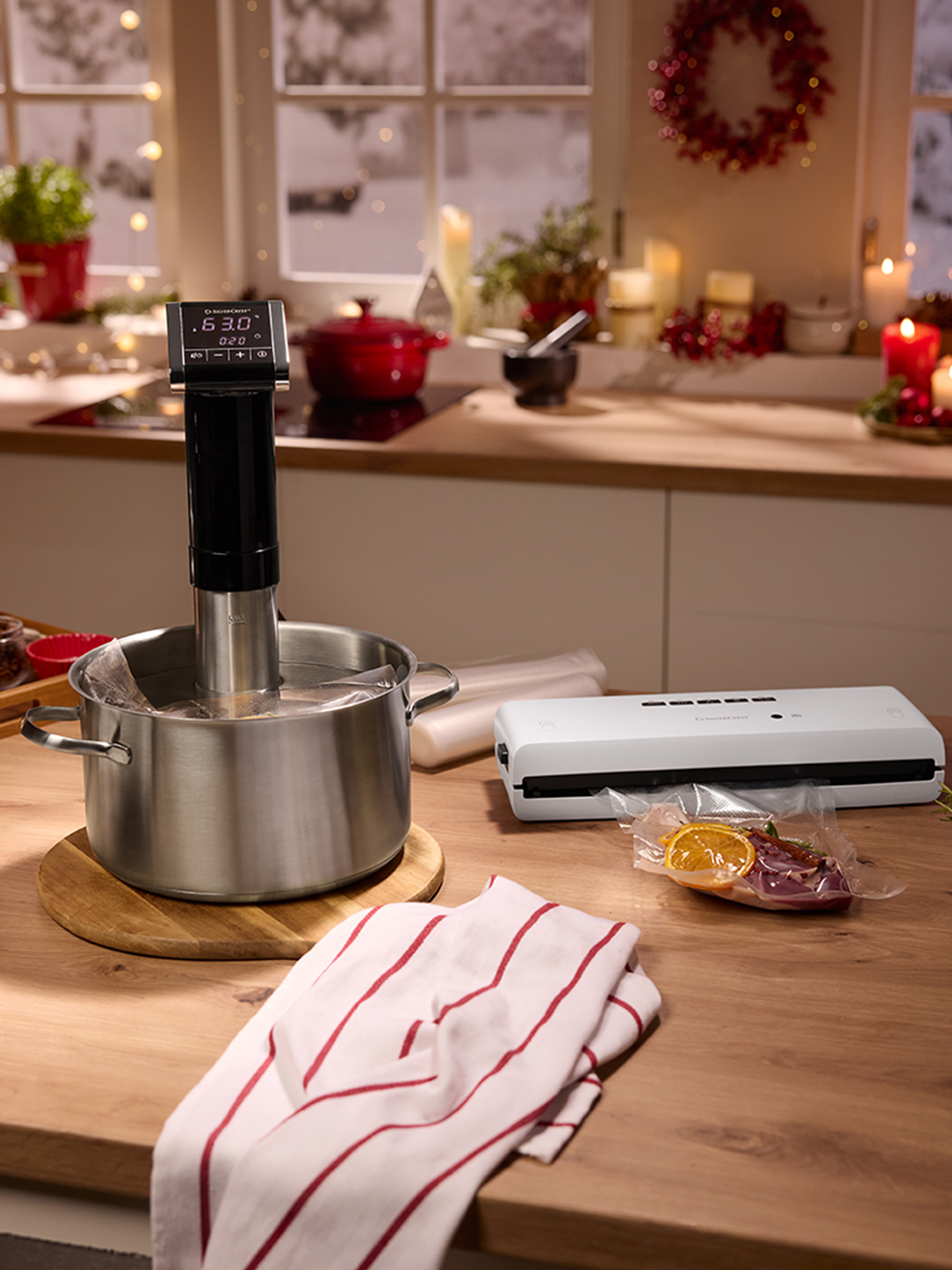 Sous vide-koker en vacuümapparaat op een aanrecht met feestelijke decoraties.