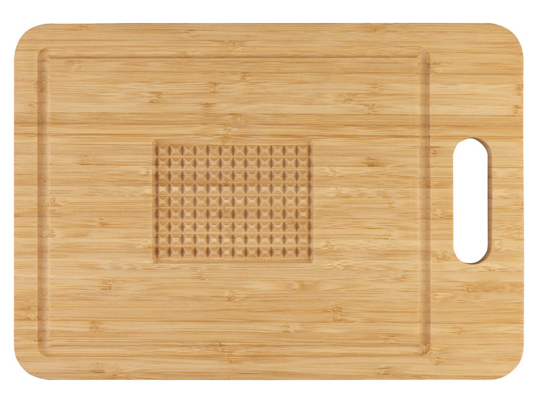Een houten snijplank met een handvat en een gegraveerd gebied.