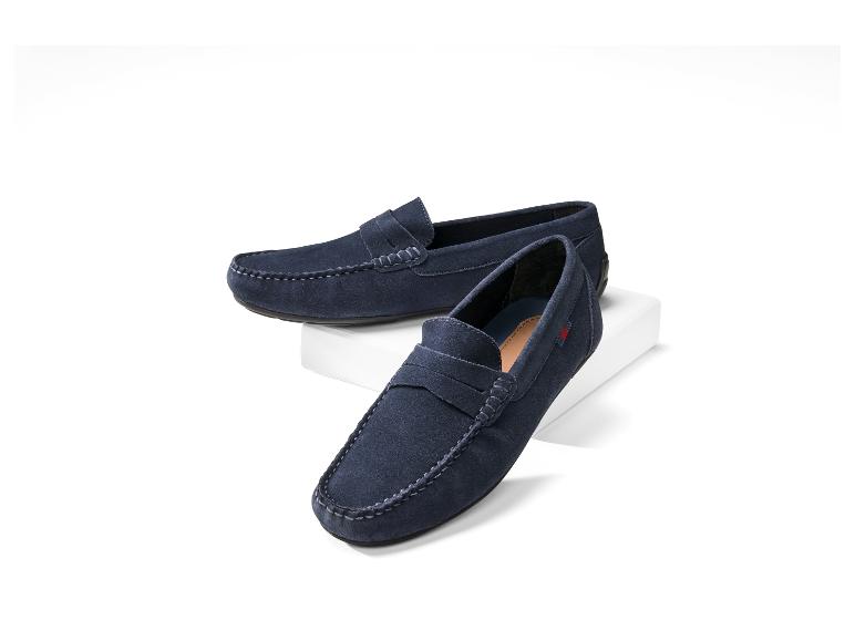 Twee marineblauwe suède herenloafers op een witte sokkel.