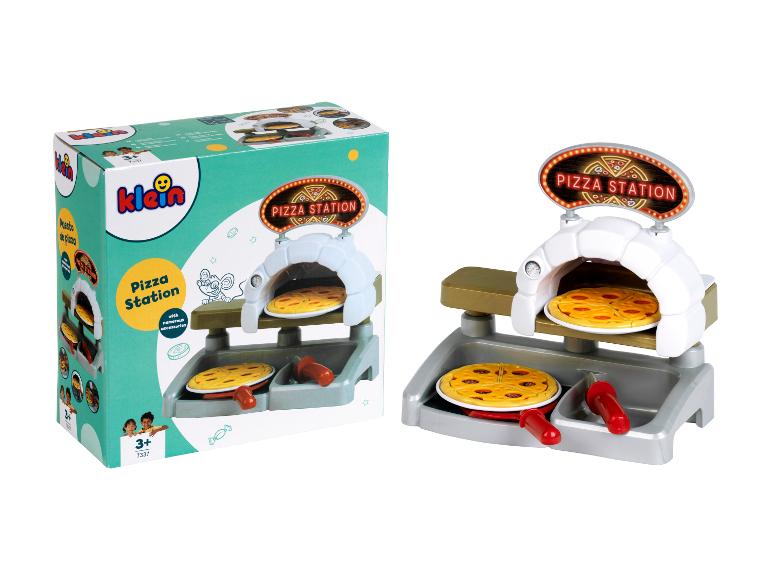 Een speelgoed pizzastation met oven, twee pizza's en accessoires, naast de verpakking.