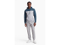 Man in een tweekleurige hoodie en grijze joggingbroek met witte sneakers.