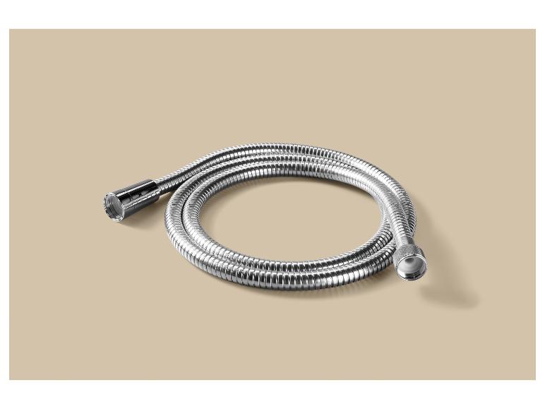 Zilveren metalen doucheslang opgerold op een beige achtergrond.