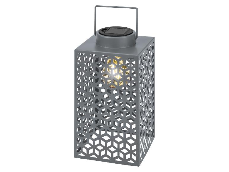 Grijze solarlantaarn met geometrisch design en warm licht.