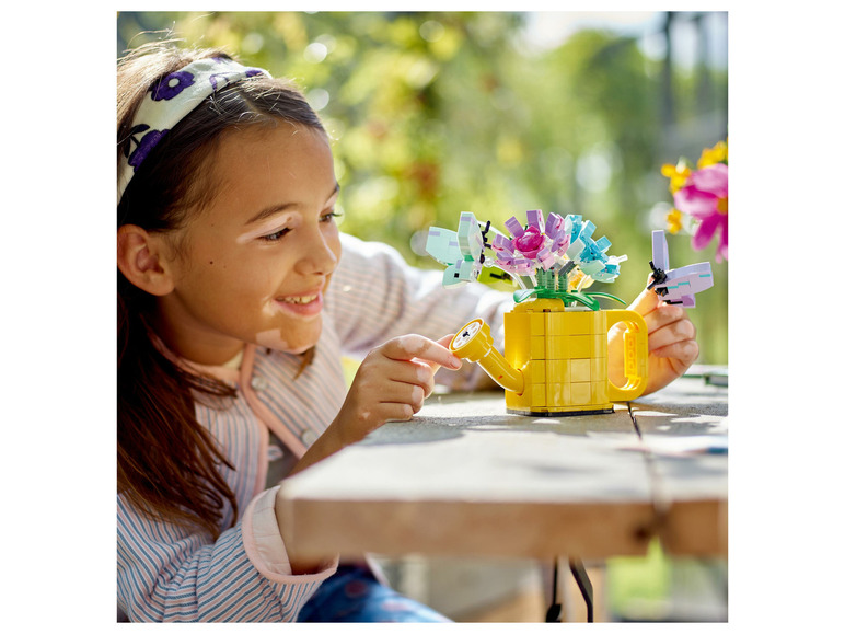 Een kind speelt met LEGO bloemen en een gieter.