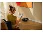 Vrouw bedient een robotstofzuiger met haar smartphone in een woonkamer.
