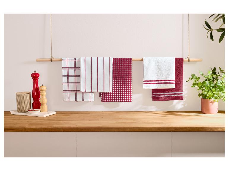 Rood-witte theedoeken hangen aan een houten stang in een keuken.