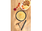 Pannenkoek in pan, ernaast bord met pannenkoeken, bananen, aardbeien en jam.