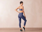 Een vrouw draagt een blauwe sportbeha en leggings met een abstract print.