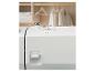 Naaimachine met zwarte draad en kledingkast met witte kleding op de achtergrond.