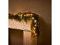 Kerstslinger met warmwitte LED-verlichting op een witte schouw.