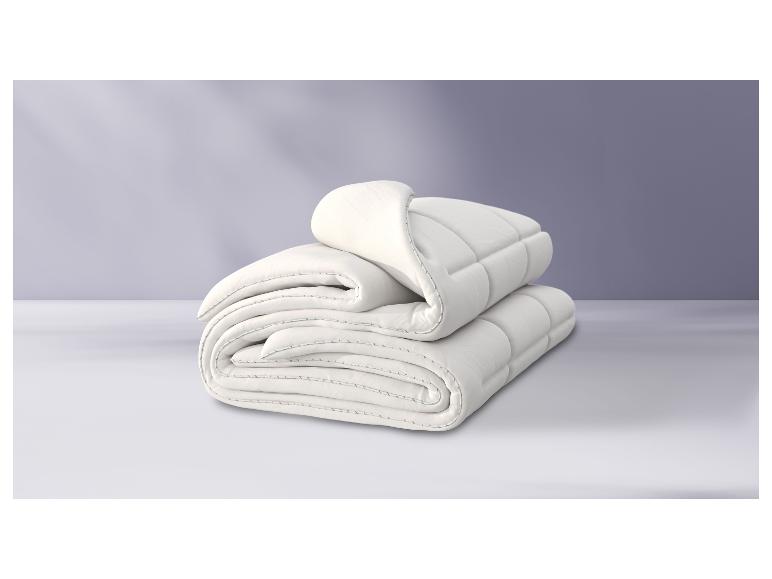Twee witte dekbedden gevouwen op een witte achtergrond.
