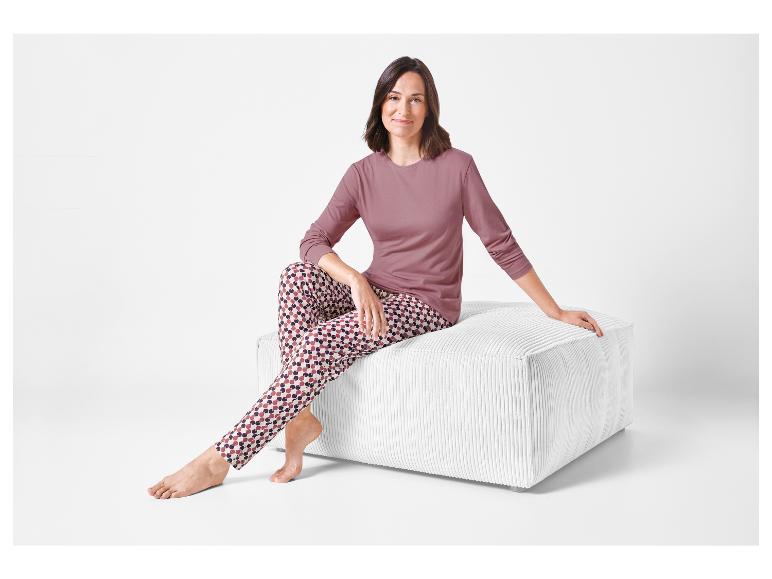 Een vrouw draagt een roze longsleeve en een pyjamabroek met een geometrisch patroon.