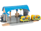 Speelgoedtreinstation met gele trein, conducteurfiguur en blauw dak.