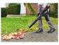 Persoon met bladblazer verwijdert bladeren van een geplaveid pad.