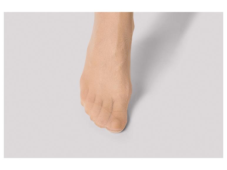 Een close-up van een voet met huidkleurige panty's.