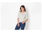 Vrouw in een wit T-shirt met knopen op de schouders en donkerblauwe jeans