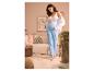 Zwangere vrouw in ESMARA® mousseline zwangerschapsbroek en witte top, houdt buik vast in gezellige kamer.