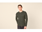 Man in groen shirt met lange mouwen, knopen en zak, poserend tegen lichte achtergrond.