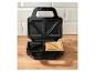 Open tosti-apparaat met een geroosterde tosti erin, op een houten ondergrond.