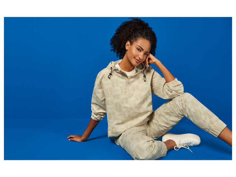 Een vrouw draagt een beige Lidl trainingspak.