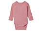 Een roze baby-romper met lange mouwen.