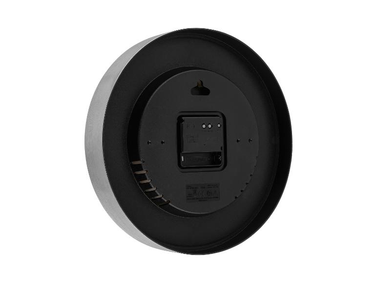 Achteraanzicht van een ronde wandklok met een geborsteld metalen frame en een zwarte plastic achterkant, met het batterijvak en de instellingen.