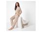 Vrouw in beige loungewear-set zit op een witte, getextureerde stoel.