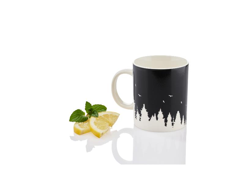Een zwarte mok met een bosprint en citroen- en muntblaadjes.