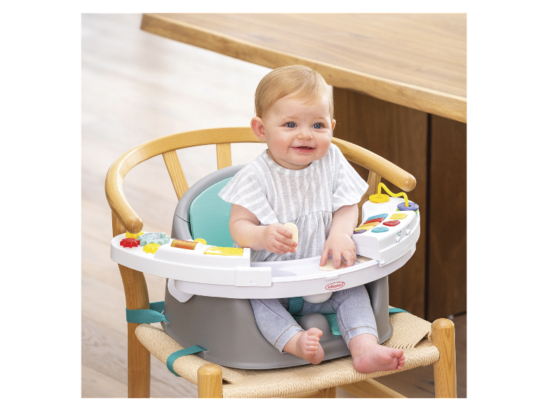 Baby in een Infantino kinderstoel met speelblad.