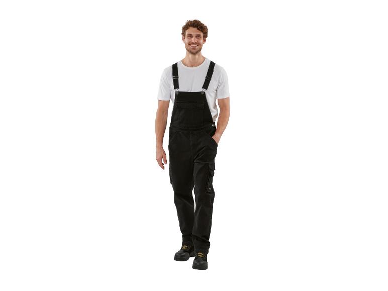 Lachende man in zwarte tuinbroek en wit T-shirt.