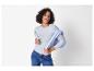 Vrouw in een lichtblauw geribbeld T-shirt met lange mouwen en jeans, met een lichtblauwe sweater over haar schouders.