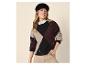 Lachende vrouw in argyle trui, wit overhemd en zwarte baret.
