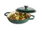 Groene gietijzeren pan met deksel, gevuld met geroosterde aardappelen, champignons en lente-uitjes.