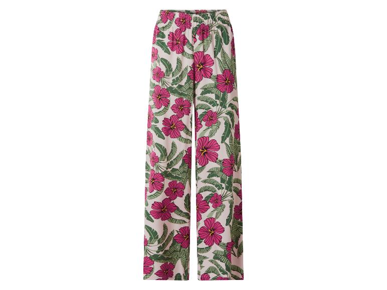 Damesbroek met wijde pijpen en tropisch patroon van roze hibiscus en groene bladeren.