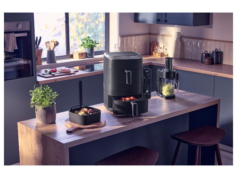 Keukenblad met airfryer, groentesnijder en verse groenten.