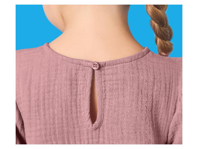 Achterkant van een roze kinderblouse met knoop in de nek en een vlecht