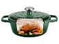 Groene gietijzeren pan met een gebraden kip, knoflook en kruiden erin, met stoom.