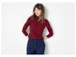 Vrouw in een rode geribbelde coltrui en marineblauwe broek