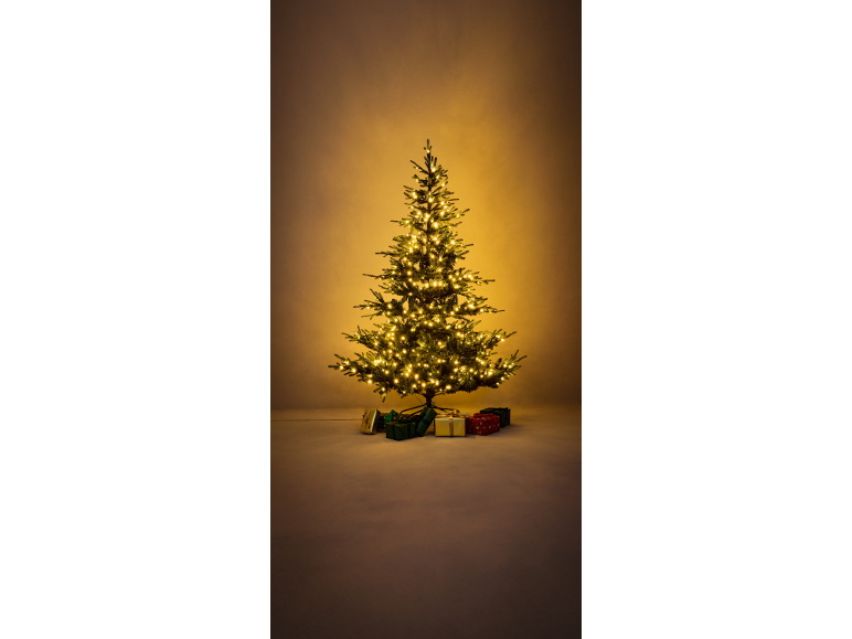Een verlichte kerstboom met cadeaus eronder, tegen een warme, gloeiende achtergrond.