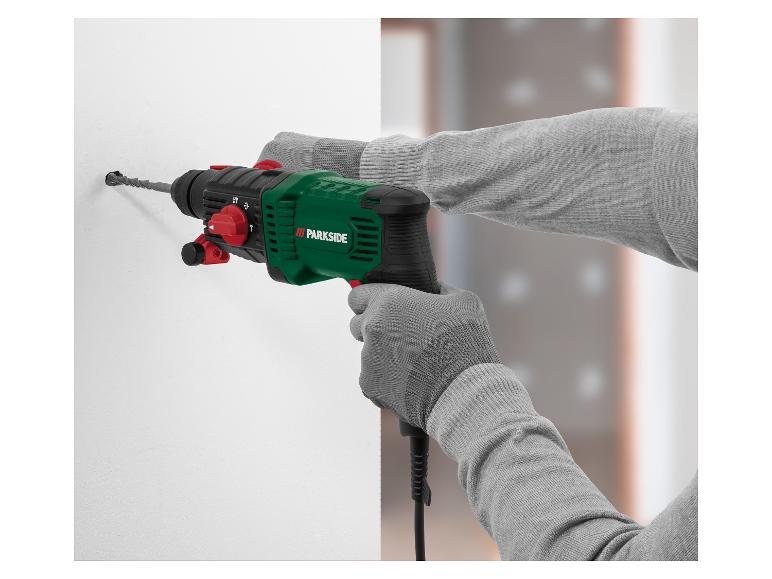 Groene en zwarte Parkside klopboormachine boort in een witte muur.