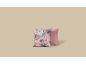 Twee decoratieve kussens, één roze met bloemenpatroon en één effen roze.